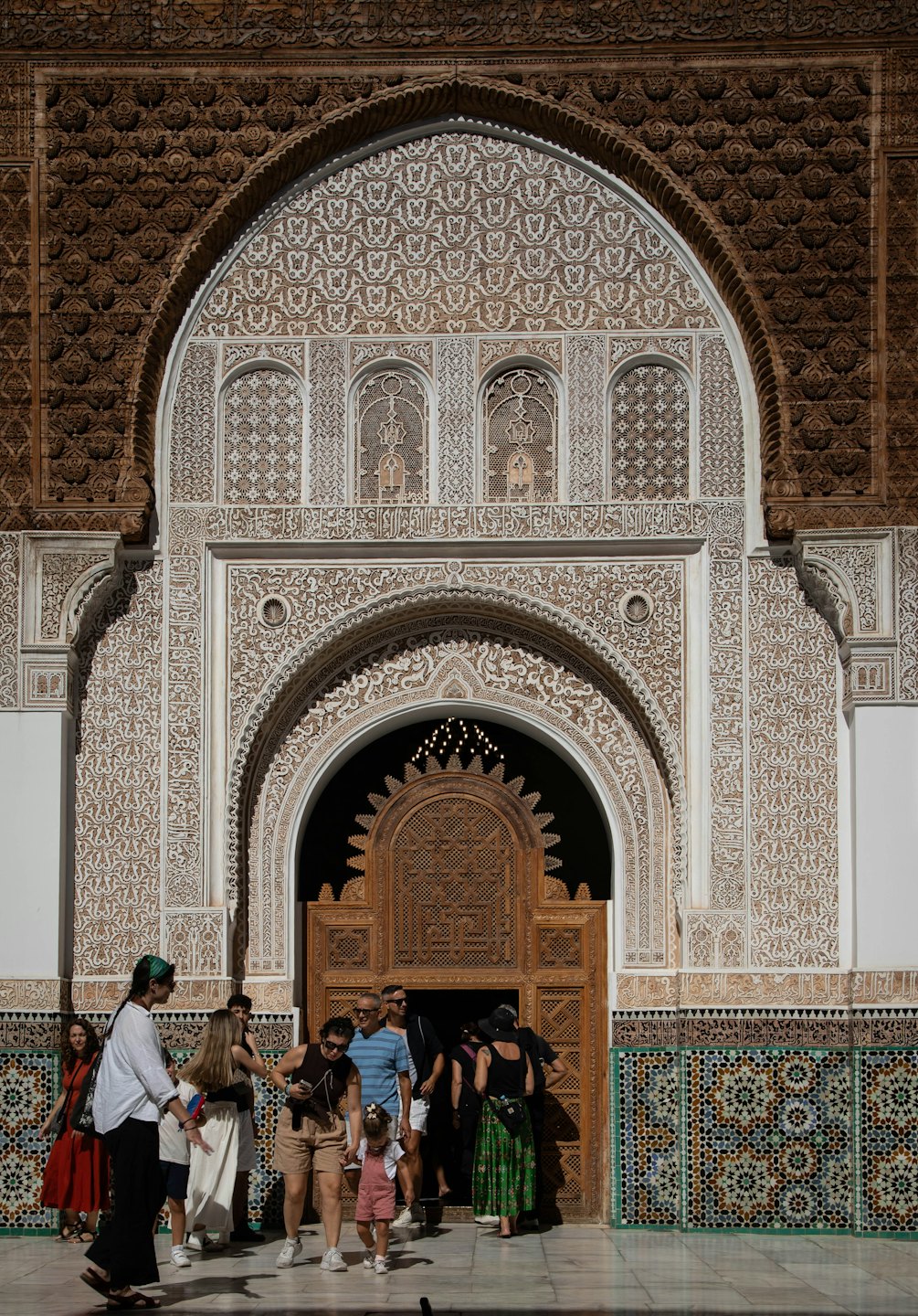Turistas atraviesan una ornamentada puerta arqueada con intrincados relieves.