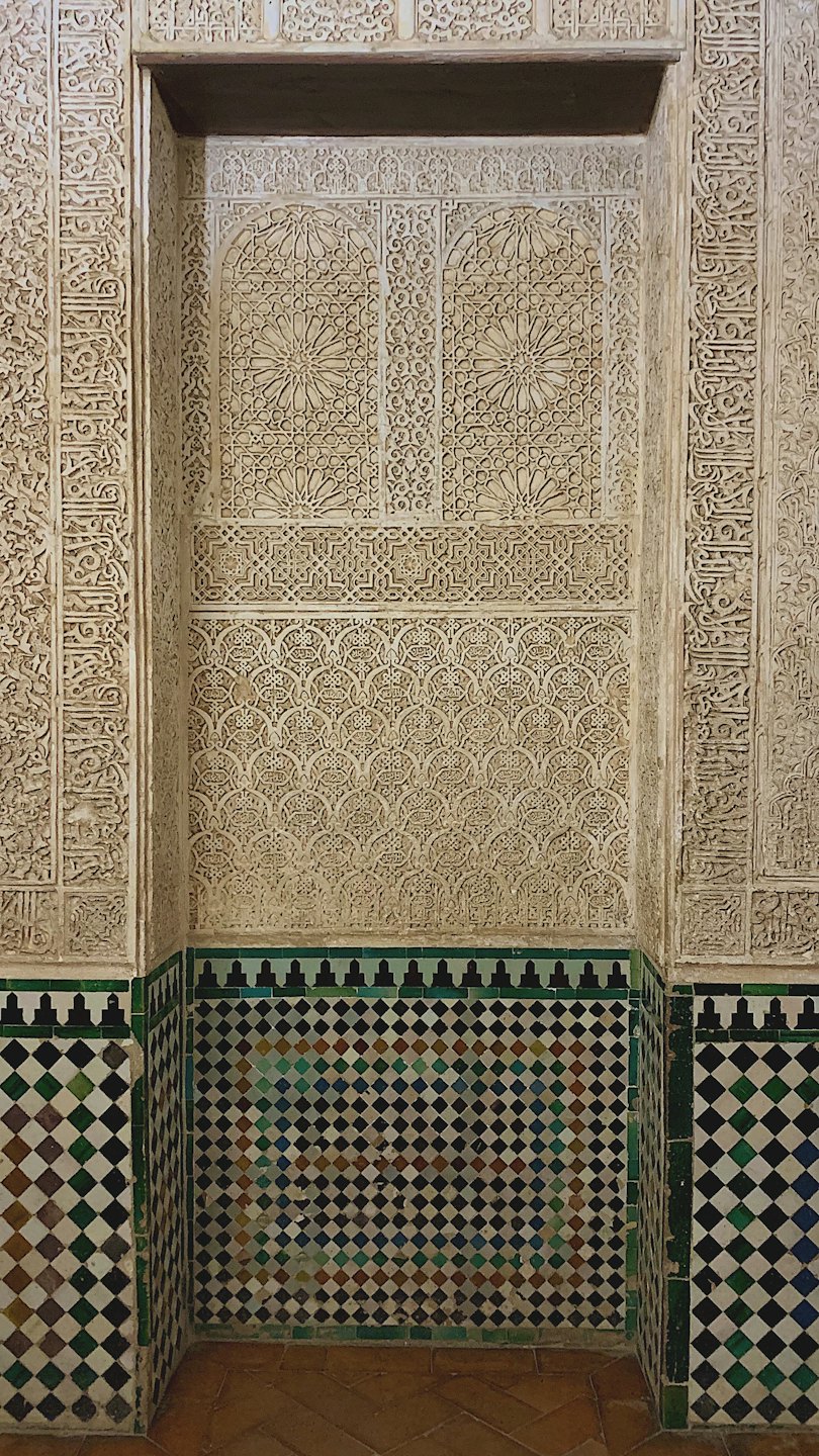 Tallado intrincado de estuco y azulejos de cerámica con patrones en una pared.