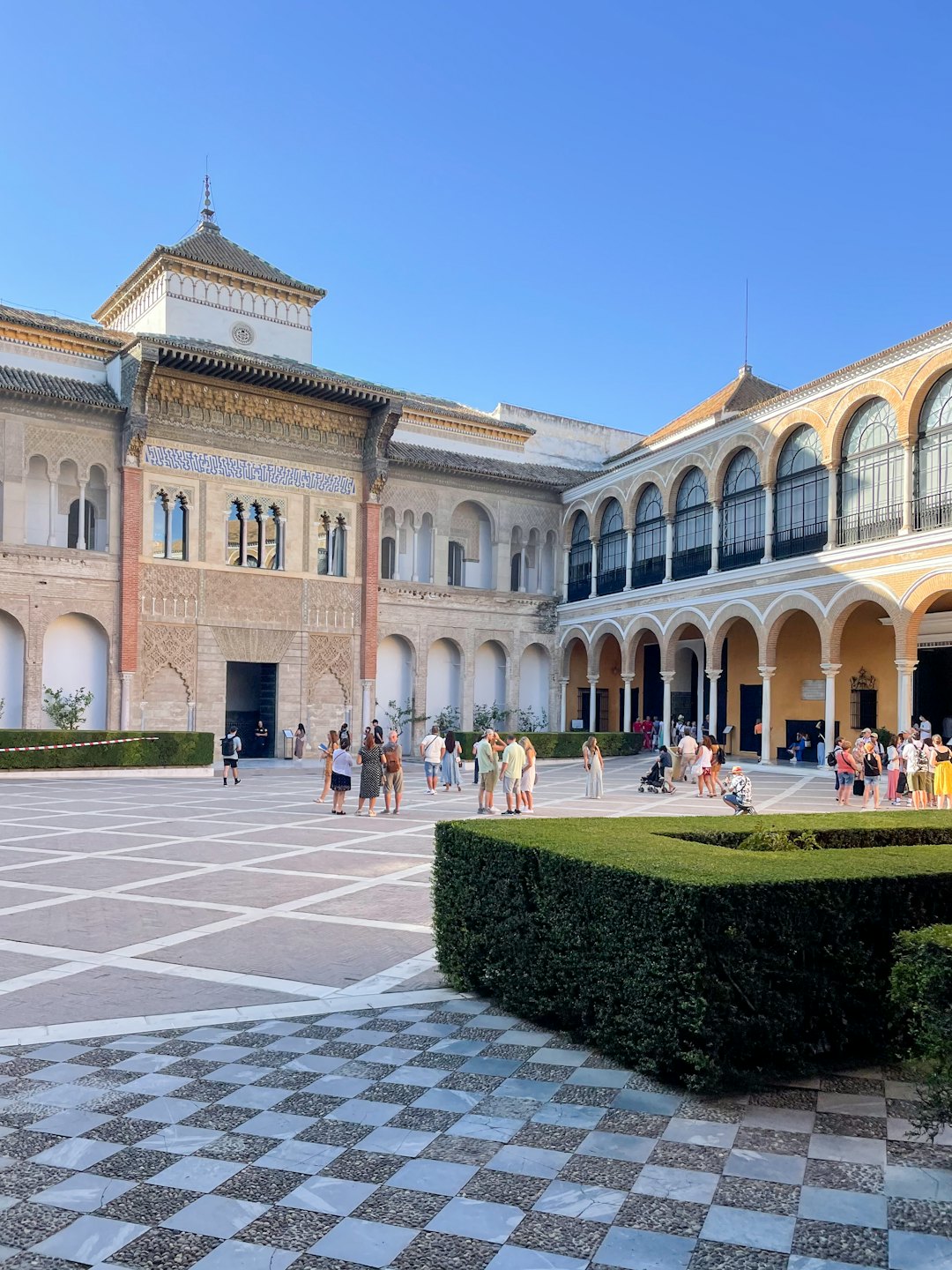 Visitantes en un patio soleado de un palacio morisco con arquitectura ornamentada.