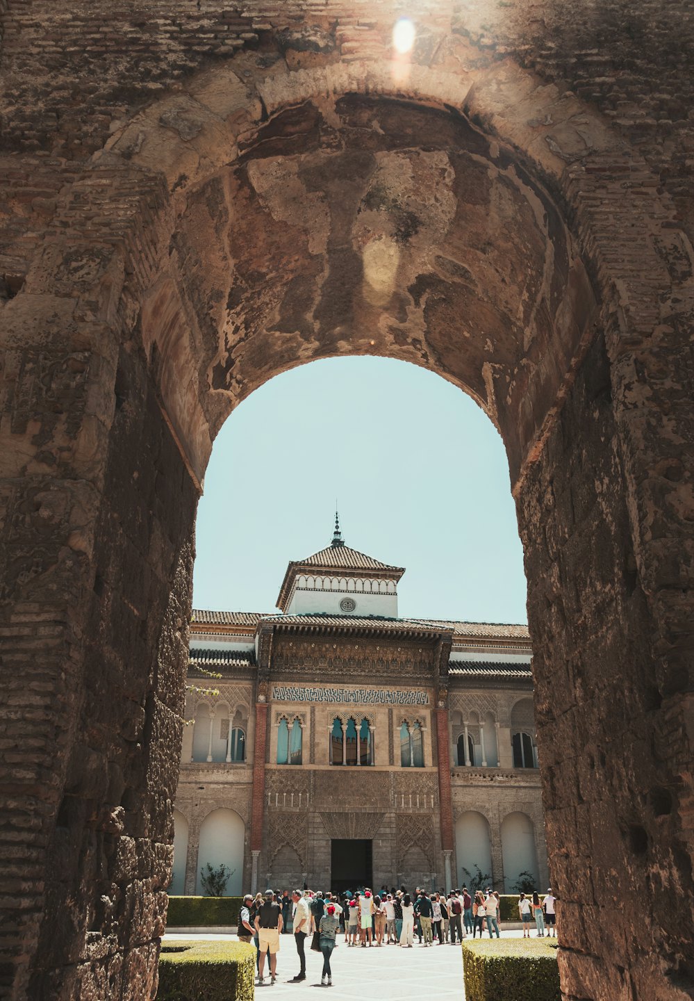 Turistas exploran un edificio mudéjar histórico a través de un arco de ladrillo.